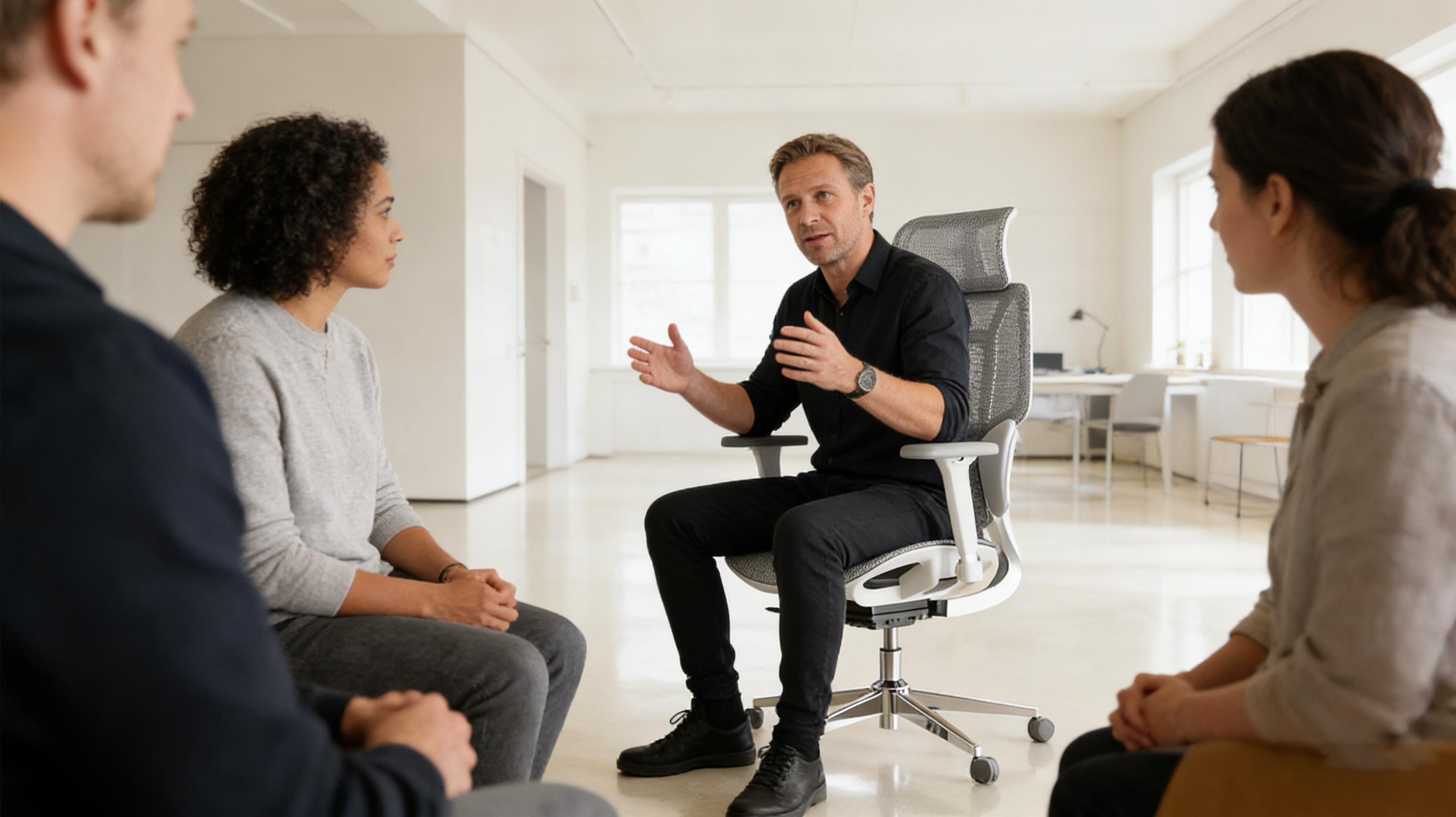 A senior brand strategist in a London loft studio sitting in a black ergodynamic office chair.