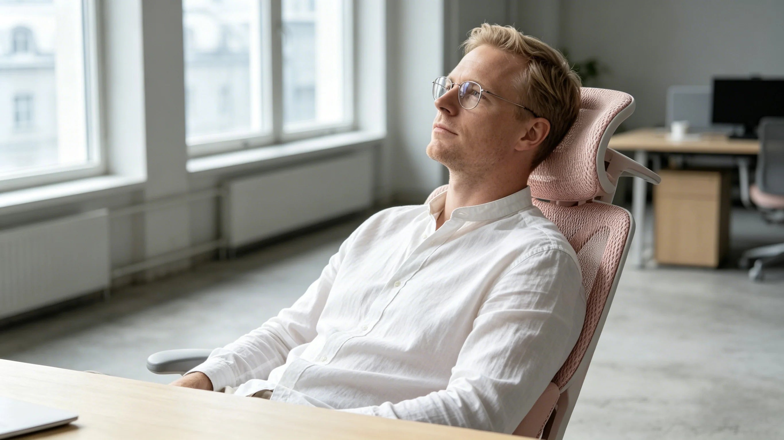 Soren working at a white minimalist desk with his pink [back support desk chair].