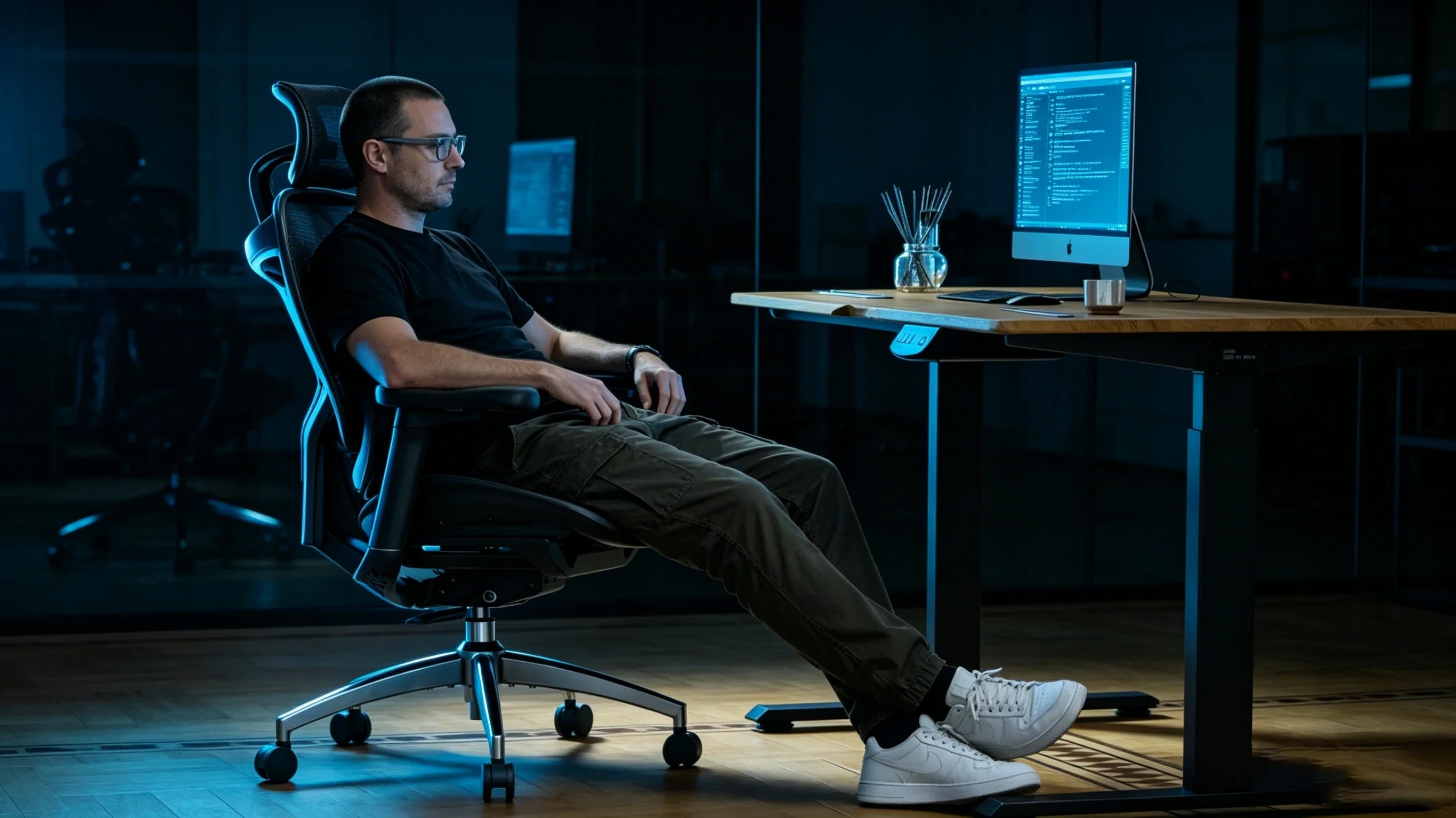 Full body view of a 40-year-old Caucasian male software architect in a black tech-tee sitting in the [office seat back support].