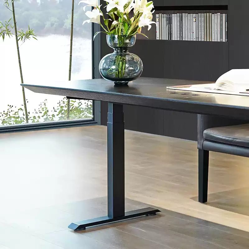 Electric standing desk desktop detail with cable grommet and wood finish