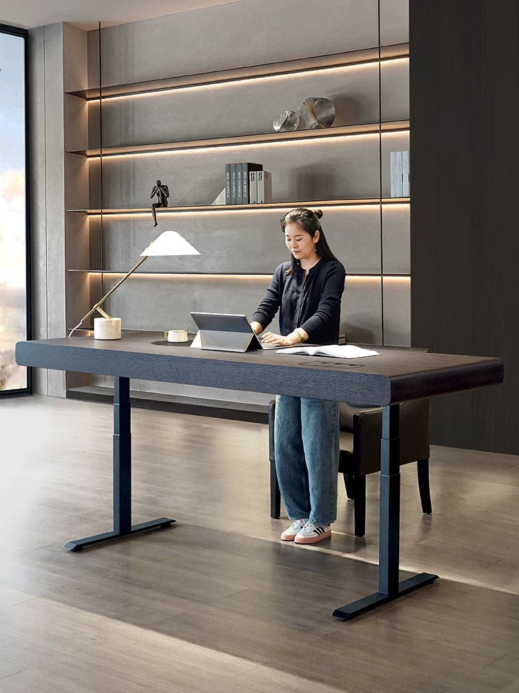 Large electric standing desk with dark wood desktop used as an executive workspace