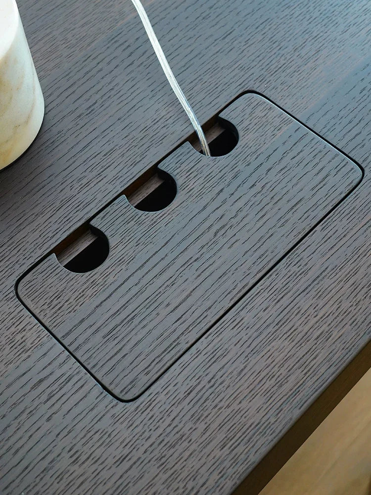 Close-up of cable access on the dark wood desktop of an electric standing desk